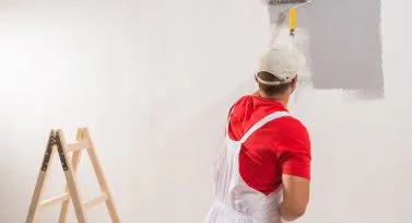 Worker priming gray walls for a fresh coat of paint in home in Lincoln